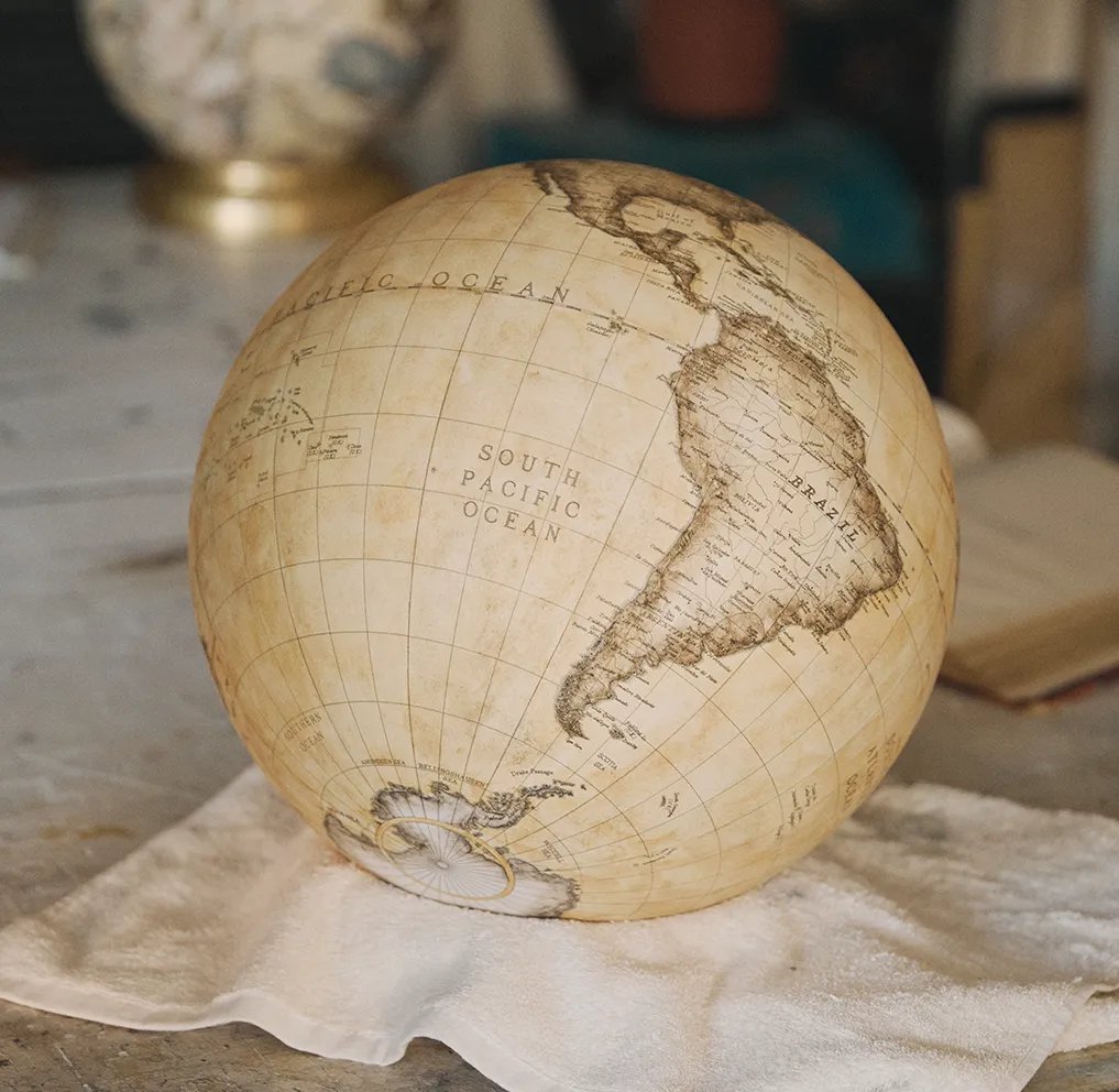 A finished sphere resting on a cloth on the studio bench, South America facing out