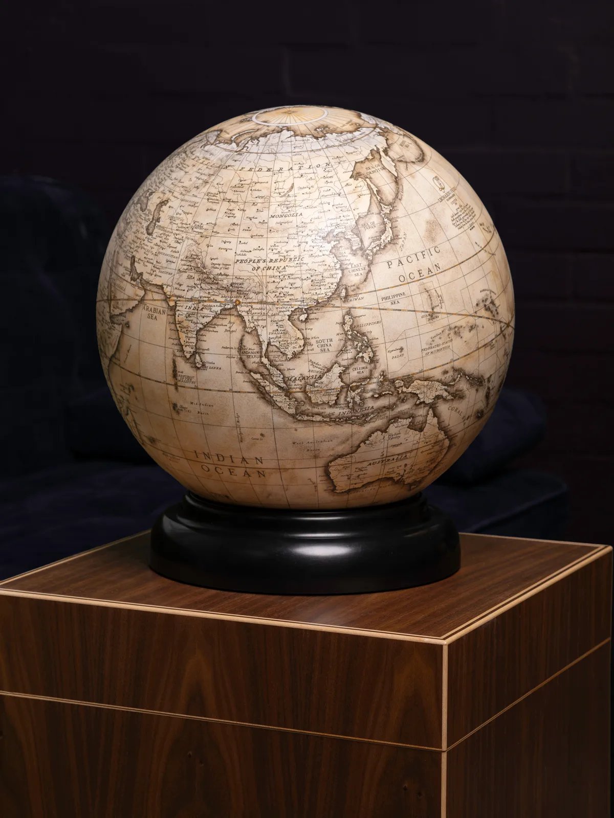 The globe on its black stand, atop a walnut cabinet