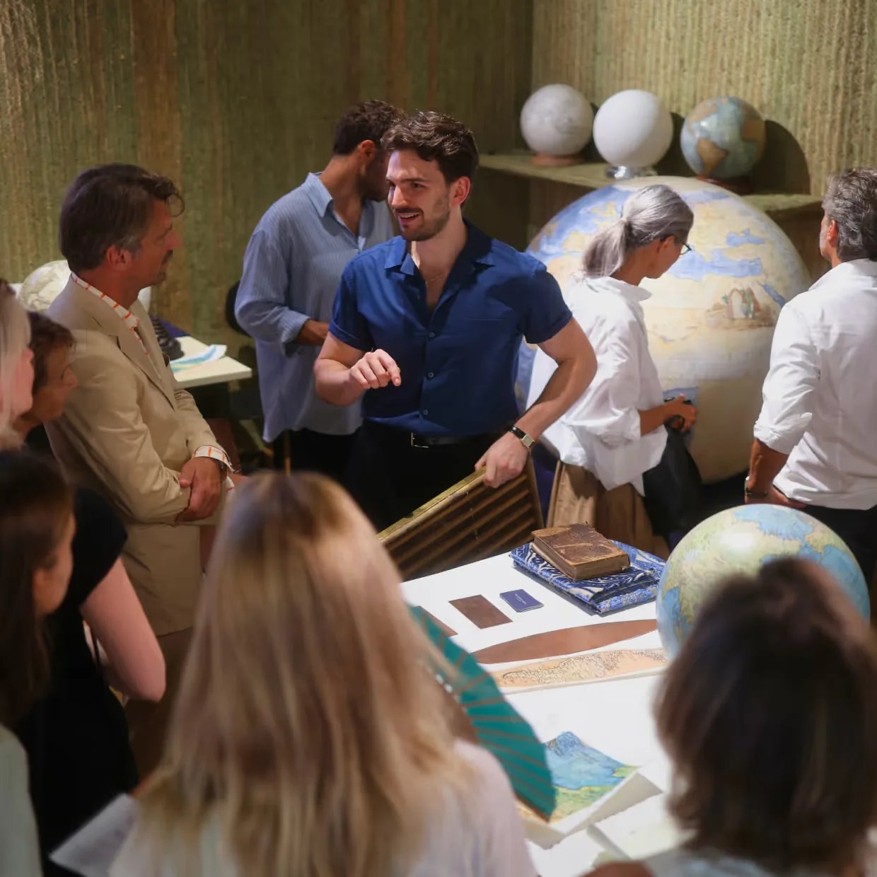 Leonardo Frigo presenting his globes to visitors in the studio, a large sphere behind him