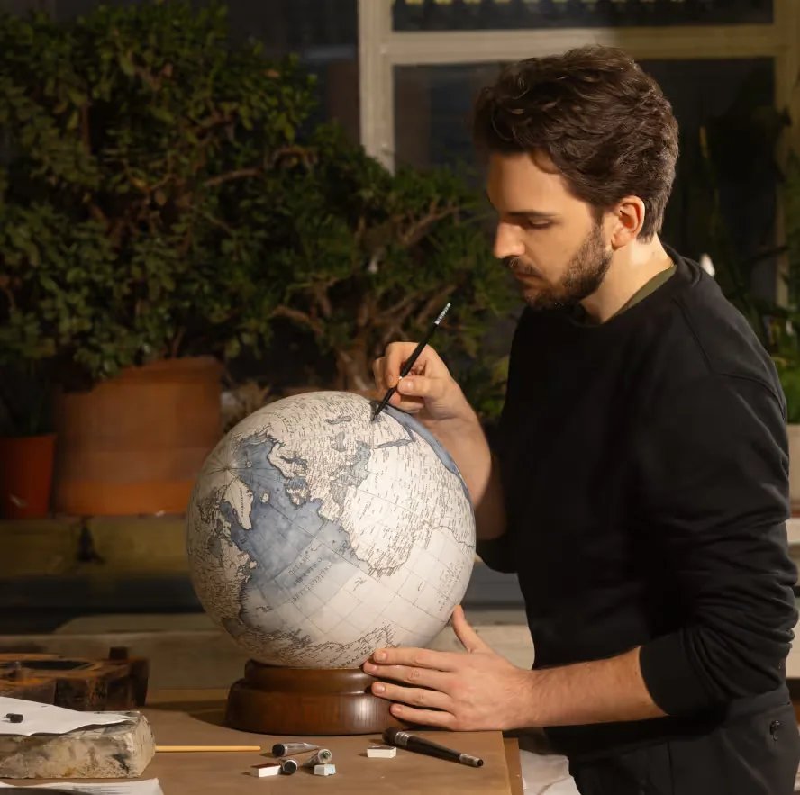 Leonardo Frigo painting a globe in his studio